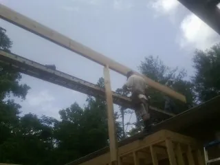 Carpenter setting a ridge beam over a new addition frame — Ice Dam Removal by Roofing Brothers in Walkertown