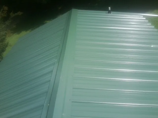 New green metal panels meeting at the ridge of a roof — Flat Roof Repair work by our crew in Walkertown