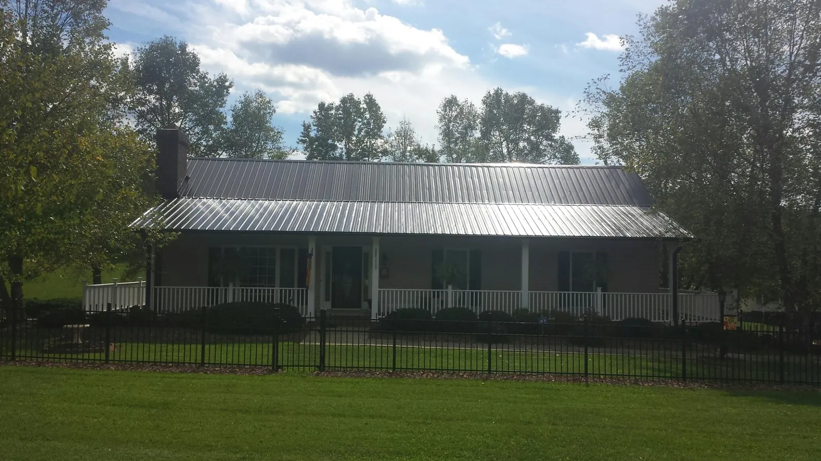 Gray metal roof on a brick ranch with a full width front porch — Gutter Guard Installation work by our crew in Walkertown