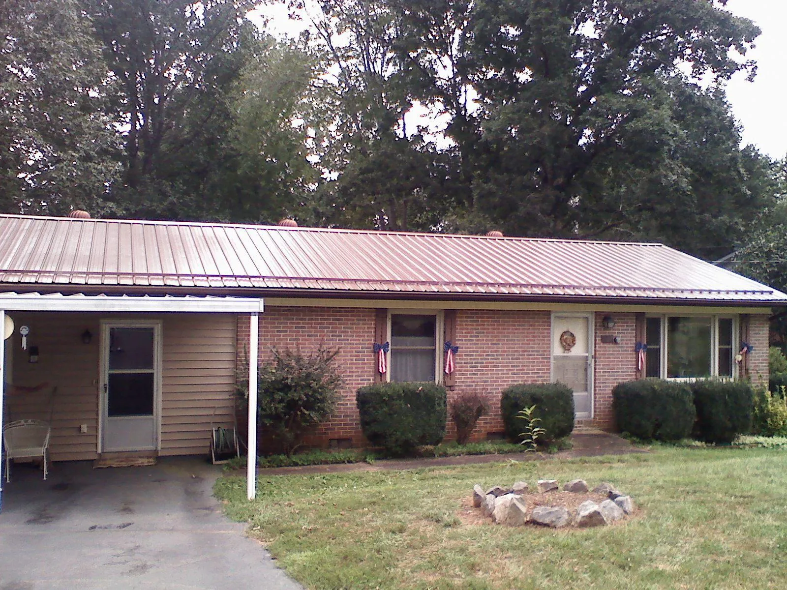 Bronze metal roof and carport on a brick ranch home — Roof Repair work by our crew in Walkertown