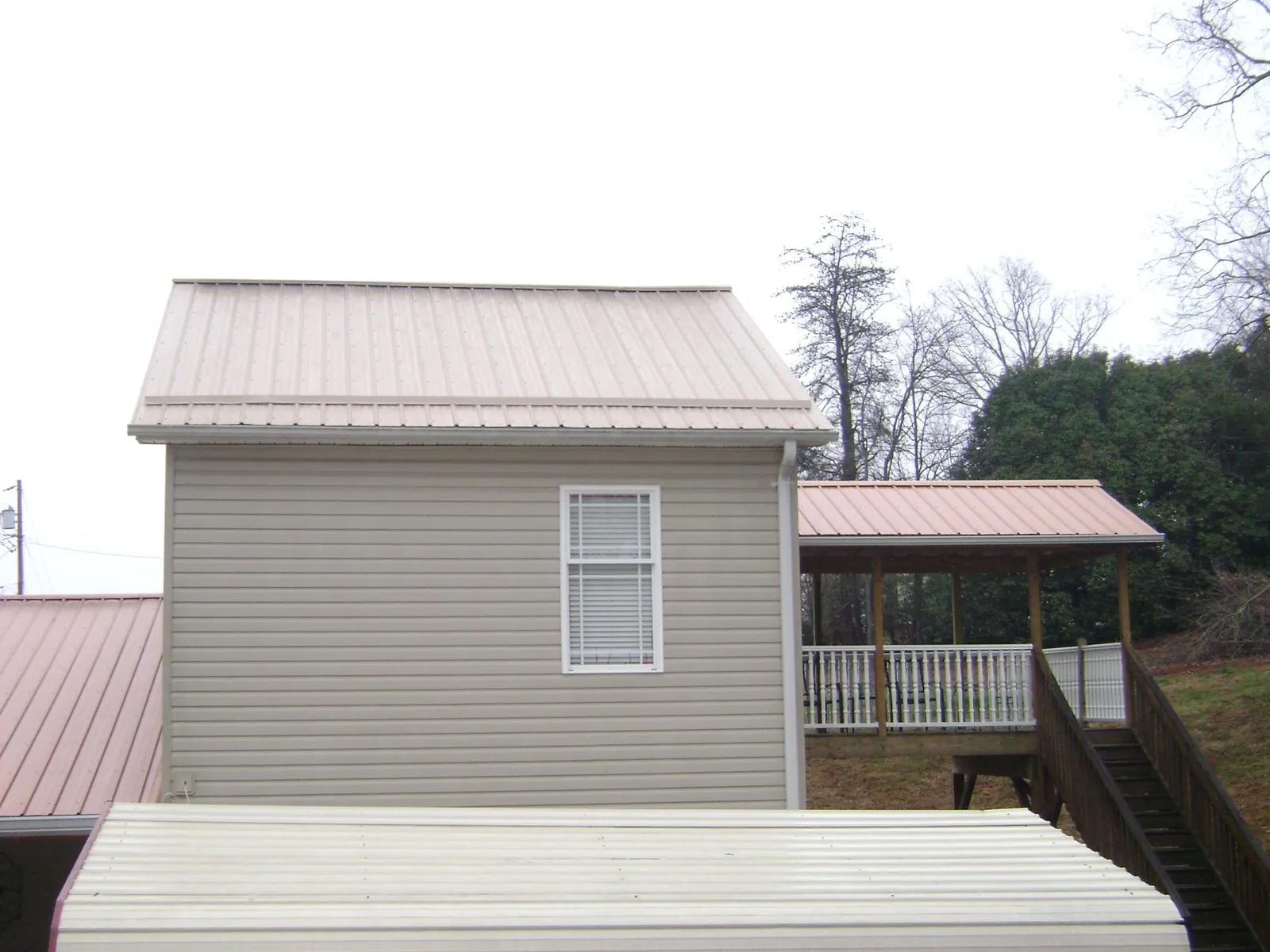 Tan metal roofs on a two story addition and attached porch, from a Roof Replacement job in Walkertown